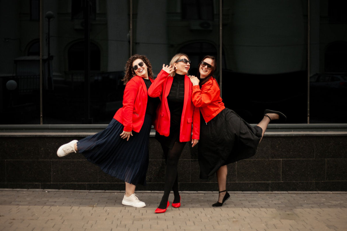 Three women exuding joy and style in vibrant red jackets, striking a pose outdoors.