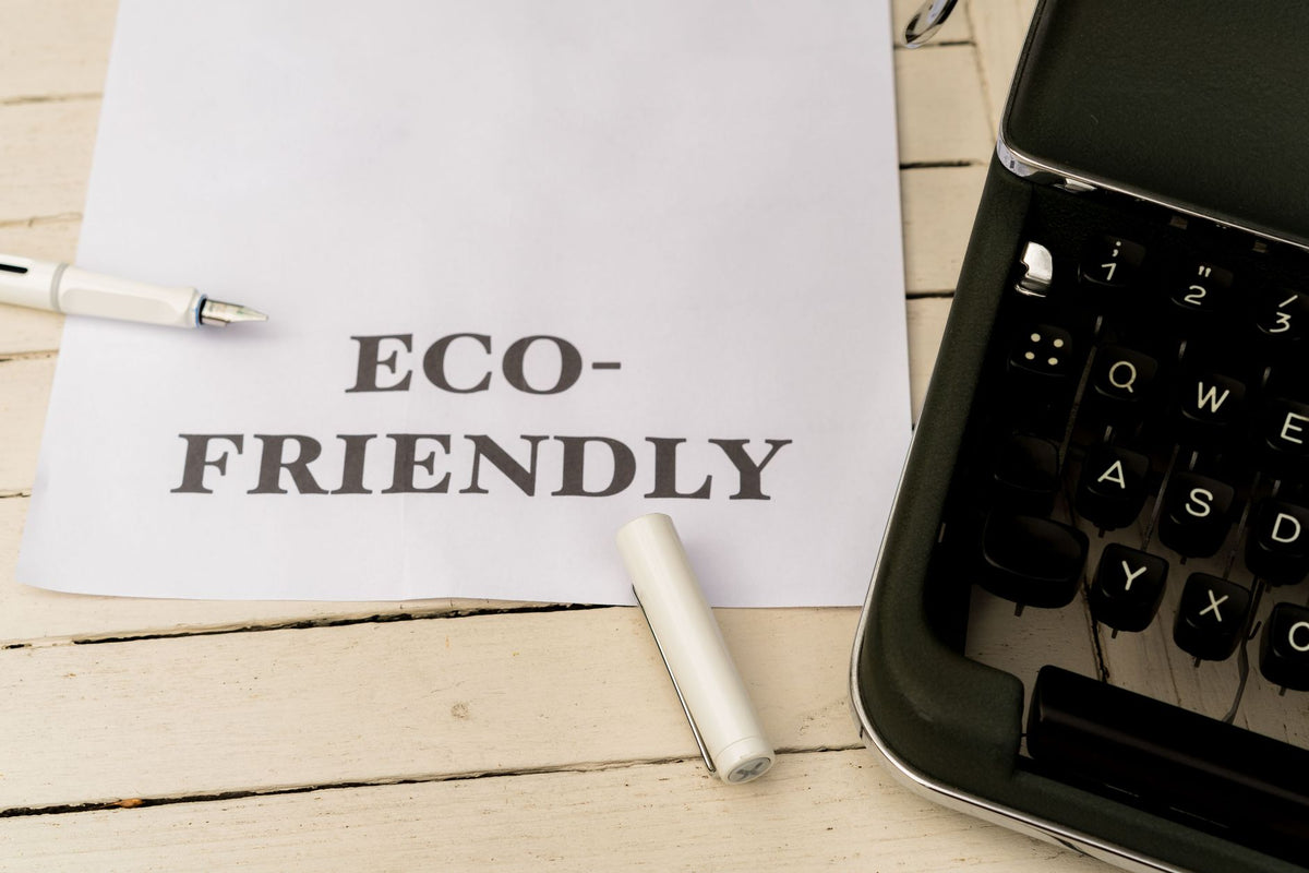 Image of eco-friendly text on paper with a vintage typewriter and pen on a wooden desk.