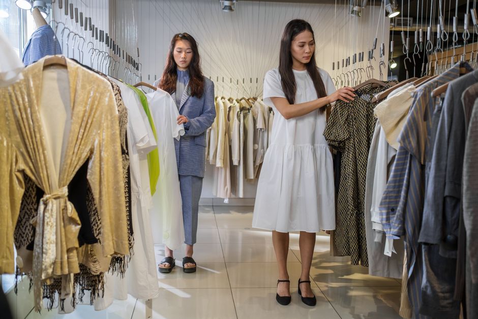 Two women browsing stylish clothes in a modern boutique.
